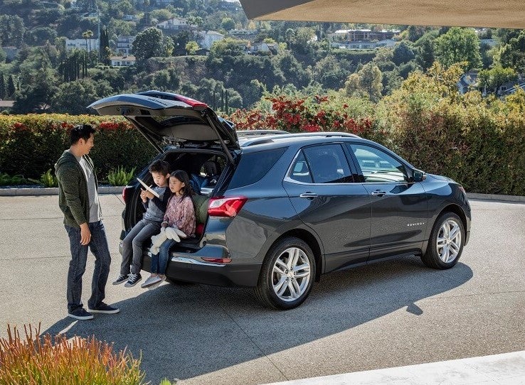 a parent and two children sit on the tailgate of their family crossover chevy equinox