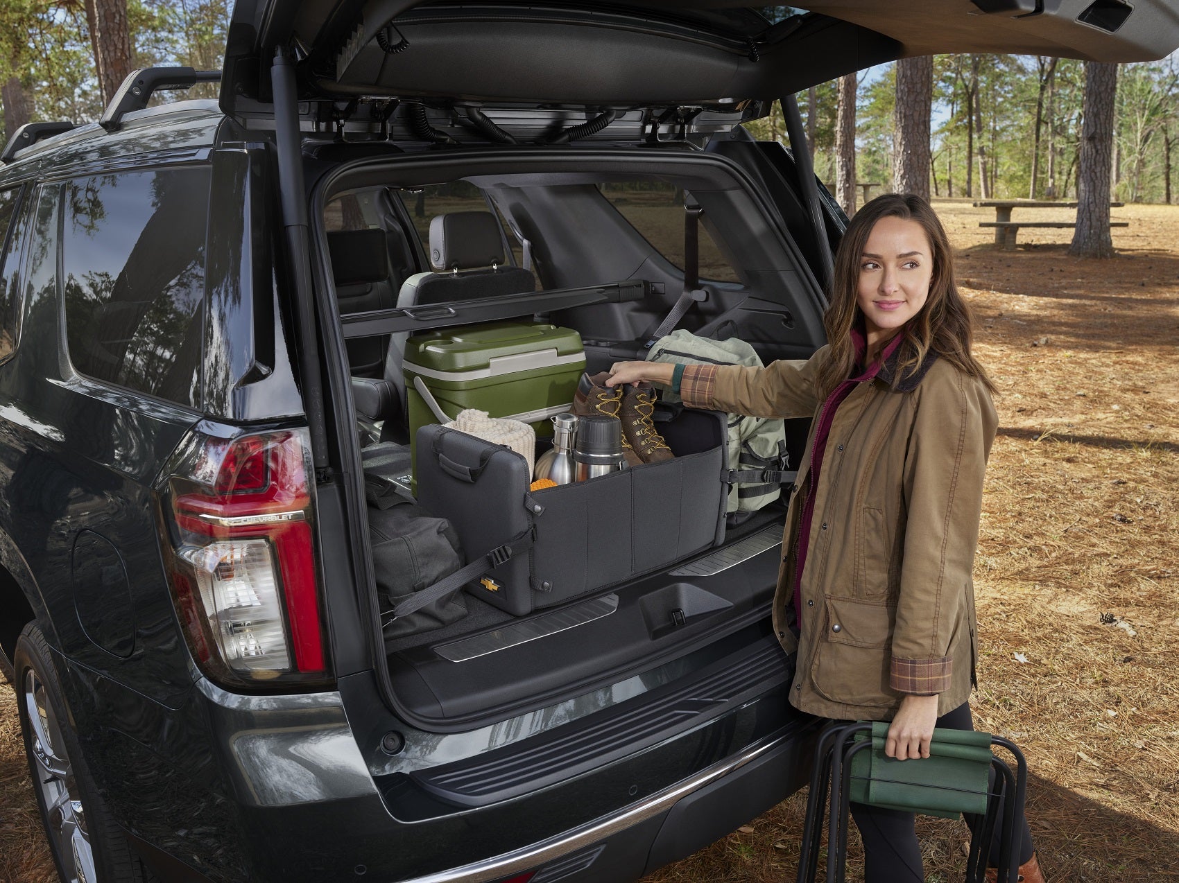 woman upacks tightly-packed chevy tahoe cargo space at a campsite