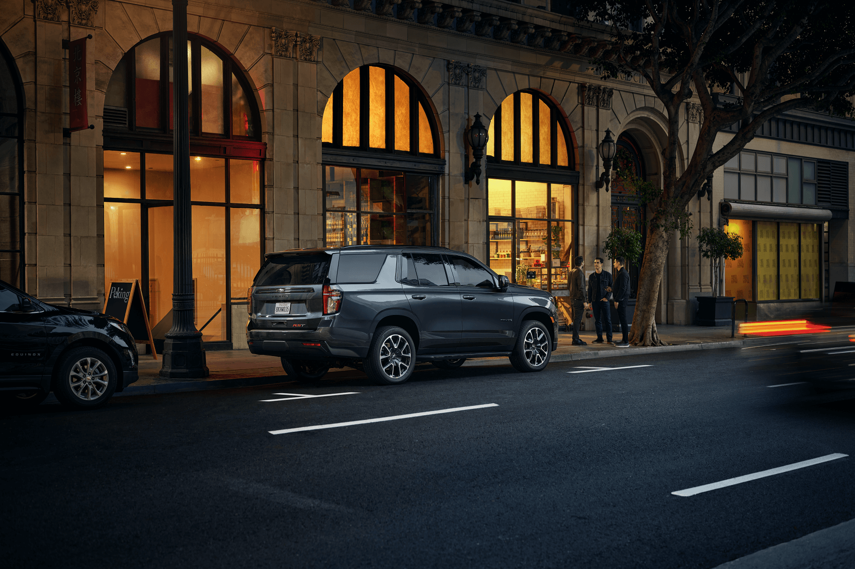 black chevy tahoe parked in front of a row of restaurants and shops on a city street