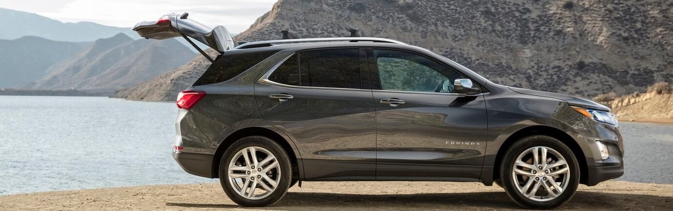 silver chevy equinox parked with its tailgate open at the edge of a lake